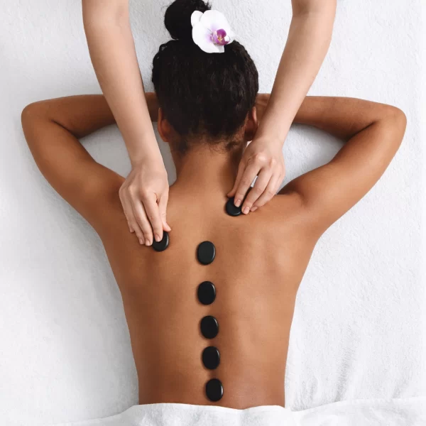 Mulher recebendo massagem com pedras quentes nas costas em clínica de estética em Indaiatuba-SP